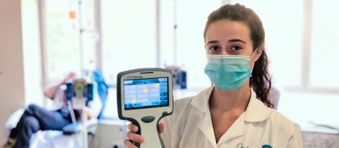 Picture of a female doctor with a mask holding a handheld virtual assistant